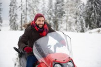 Young man riding snowmobile in winter — Stock Photo