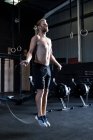Hombre ejercitándose en el gimnasio, saltando con la cuerda de la velocidad - foto de stock