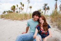 Портрет молодої пари, сидячи на пляжі — стокове фото