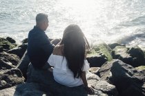 Coppia seduta su rocce costiere, guardando la vista, vista posteriore — Foto stock