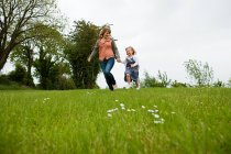 Mother and daughter running on green field — Stock Photo