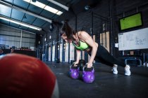 Mujer ejercitándose en el gimnasio, usando pesas - foto de stock