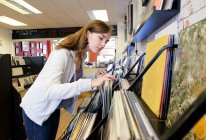 Молода жінка дивиться на складені вінілові записи в магазині рекордів — стокове фото