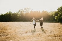 Casal caminhando no campo de grama dourada, Arezzo, Toscana, Itália — Fotografia de Stock