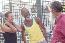 Трое взрослых мужчин смеются на баскетбольной площадке — стоковое фото
