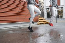 Male twins skipping with ropes on sidewalk — Stock Photo