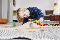 Мальчик играет с игрушечным поездом и треком — стоковое фото