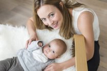 Porträt einer Mutter mit Baby auf Stuhl, die in die Kamera blickt — Stockfoto