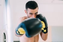 Retrato del hombre en guantes de boxeo mirando a la cámara - foto de stock