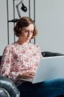 Woman in chair using laptop on lap — Stock Photo