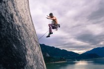 Вид збоку людини з сходження мотузки стрибати від кам'яної скелі на маламут, Squamish, Сполучені Штати Америки — стокове фото