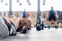 Cropped rear view of man doing push up on gym — Stock Photo