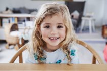 Portrait of young girl sitting at table — Stock Photo