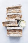 Vista dall'alto della pagnotta di pane a fette con burro su tavolo bianco — Foto stock