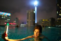 Tourist taking selfie in rooftop pool, KL Tower in background, Kuala Lumpur, Malásia — Fotografia de Stock