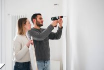 Couple drilling wall to hang picture — Stock Photo