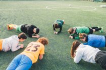 Joueurs de football en position de planche sur le terrain — Photo de stock