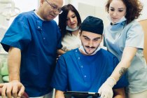 Стоматологи в стоматологічному кабінеті дивляться на цифровий планшет — стокове фото