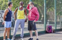 Трое взрослых мужчин разговаривают на баскетбольной площадке — стоковое фото