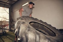 Homme soulevant gros pneu — Photo de stock