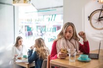 Junge Frau benutzt Smartphone und Laptop im Café — Stockfoto