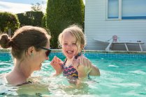 Woman holding toddler daughter hands in swimming pool — Stock Photo