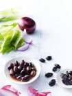 Cos lettuce, olives and red onions on white tabletop — Stock Photo