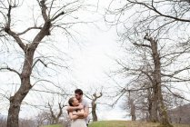 Hombre abrazando mujer en parque - foto de stock