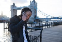 Young man outdoors, using smartphone, Tower Bridge in background, London, England, UK — Stock Photo