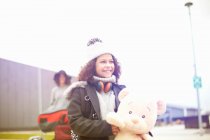 Retrato de niña sosteniendo oso de peluche mirando hacia otro lado sonriendo - foto de stock