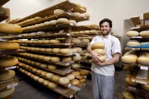 Портрет производителя сыра с твердыми сырами для осмотра, в помещении для старения, где хранятся твердые сыры — стоковое фото