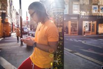 Junger Mann lehnt mit Smartphone an Laternenpfahl — Stockfoto
