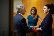 Businesswoman and man shaking hands in reception — Stock Photo