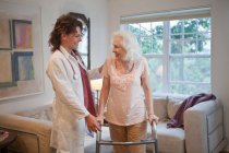 Doctor supporting senior woman on walking frame — Stock Photo