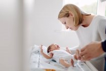 Mother and father dressing newborn baby — Stock Photo