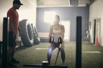 Woman in gym using exercise equipment — Stock Photo