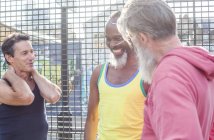 Трое взрослых мужчин смеются вместе на баскетбольной площадке — стоковое фото