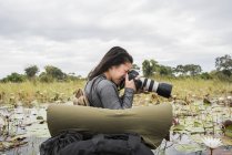 Joven turista fotografiando loto en el Delta del Okavango, Botswana, África - foto de stock