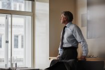 Зрілий бізнесмен в офісі дивиться з вікна — стокове фото