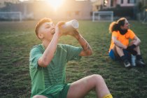 Football players taking break on pitch — Stock Photo