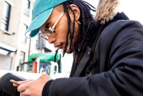 Mann mit Dreadlocks schaut auf Smartphone im Freien — Stockfoto