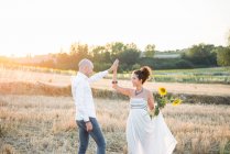 Couple in field and woman holding sunflowers — Stock Photo