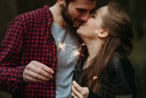 Close up de casal segurando sparklers e beijando — Fotografia de Stock