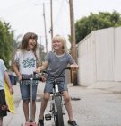Mädchen und Jungen in Bahn mit Roller, Fahrrad und Skateboard — Stockfoto