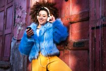 Женщина на улице слушает музыку через наушники на смартфоне — стоковое фото