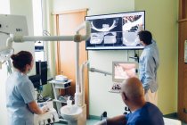 Dentista y enfermera dental mirando las radiografías dentales - foto de stock