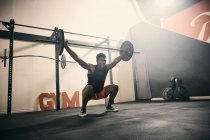 Homem no ginásio levantamento de peso usando barra — Fotografia de Stock