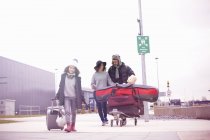 Дальний вид на отца с колёсным чемоданом и тележкой для багажа — стоковое фото