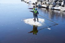 Zwei Jungen stehen auf dem Eis, auf dem See und schieben sich mit Stange — Stockfoto