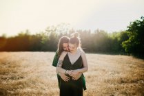 Jovem casal abraçando no campo de grama dourada, Arezzo, Toscana, Itália — Fotografia de Stock
